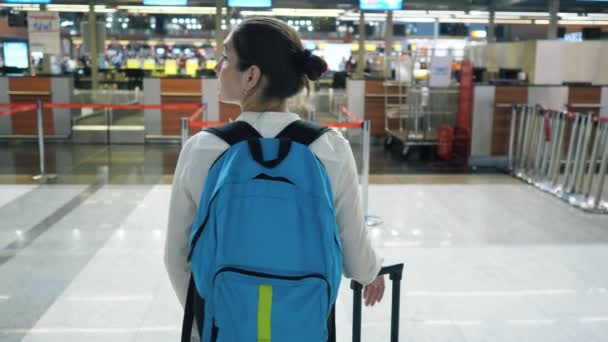 Una joven en el aeropuerto. Ella está de pie y mirando a su alrededor, vista trasera . — Vídeos de Stock