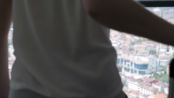 Vrouw met koffer in hotelkamer met panoramisch uitzicht op de stad, achteraanzicht. — Stockvideo