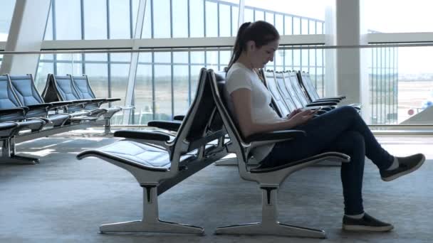 Femme est assis et naviguant smartphone dans la salle d'attente vide à l'aéroport . — Video