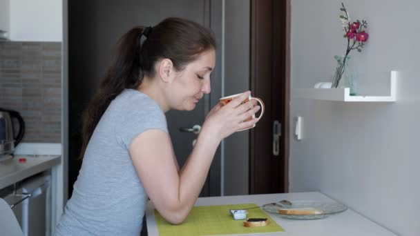 Jonge vrouw reiziger is het hebben van een ontbijt in hotelkamer. — Stockvideo