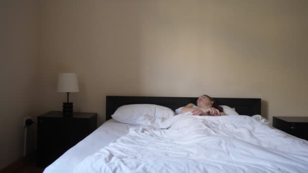 Vrouw wordt wakker in de ochtend, zittend en stretching in bed. — Stockvideo