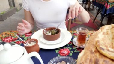 Kadın geleneksel Azerbaycan restoranında ekşi krema ile dolma yiyor.