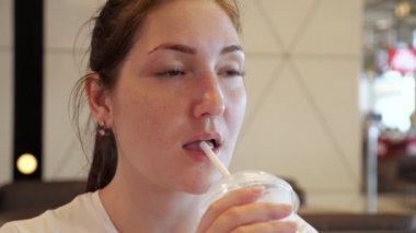Fast food kafede samandan milkshake içen genç kadının portresi.