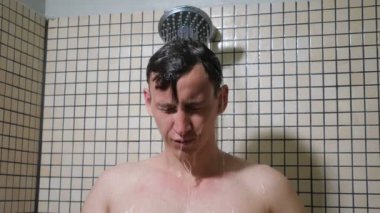 Genç adamın portresi elleriyle saçlarını tarıyor duş alıyor.