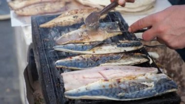 Adam sokak pazarında ızgara beyaz balık balyk kızartma, eller closeup.