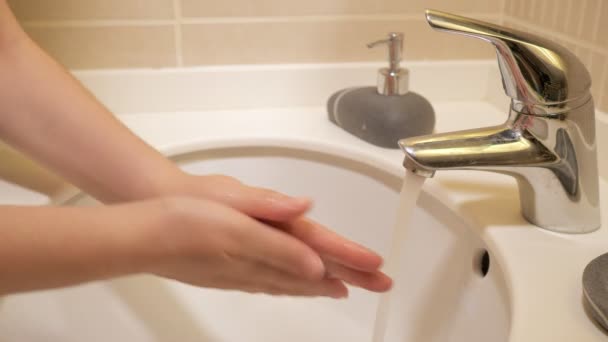 Donna sta lavando accuratamente le mani con sapone liquido nel lavandino, mani primo piano . — Video Stock