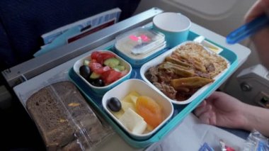 Kadın uçuş sırasında uçakta yemek yiyor bir tepside servis, el closeup.