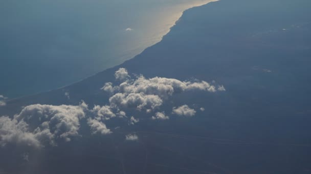 Flying over the layer of clouds and looking on landscape through the clouds. — Stock Video