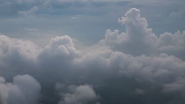 Yeşil manzara üzerinde beyaz yumuşak kabarık bulutlar, uçaktan havadan görünüm.