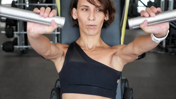 Sportowa kobieta robi ćwiczenia na mięśnie ramion na maszynie treningowej. — Zdjęcie stockowe