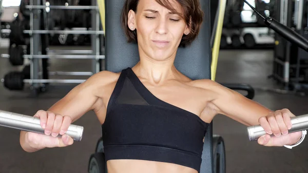 Iniciante em mulheres esportivas está trabalhando pela primeira vez em um simulador para os músculos dos braços. Recém-chegado no ginásio . — Fotografia de Stock