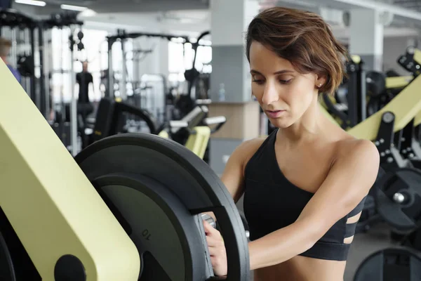 Kobieta, dodanie masy na pasku jak ona treningu w siłowni fitness — Zdjęcie stockowe