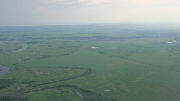 Vista aérea sobre campos verdes, bosque y río en niebla desde la ventana del avión . — Vídeos de Stock