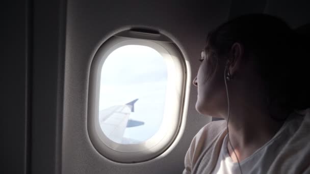 Portrait of young woman is looking at plane window. — Stock Video