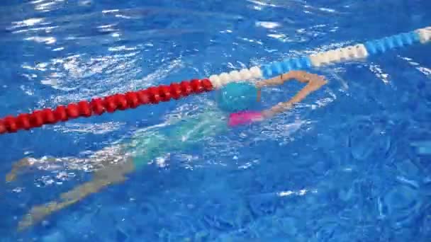 Small child girl is learning to swim in pool diving and floating in water. — Stock Video