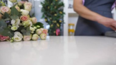Çiçekçi gül buketi sarmak için masaya bir kağıt rulo, closeup görünümü.