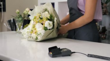 Adam çiçekçi de buket satın ödeme terminalinde kartla öder, eller closeup.