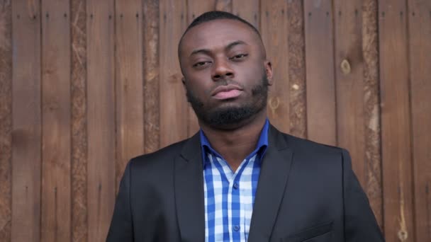 Schwarzer afroamerikanischer lächelnder Mann zeigt Geste Daumen hoch auf dunklem Holzhintergrund. — Stockvideo