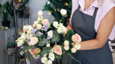 Çiçekçi kadın güller, yaprakları ve Gypsophila ile güzel çiçek buket oluşturur.