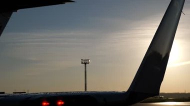 Gün batımında pistte ve radar kulesinde uçağın ıslak kuyruğu.