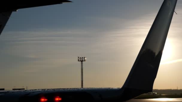 Wet tail of the aircraft on runway and radar tower in the distance at sunset. — Stock Video