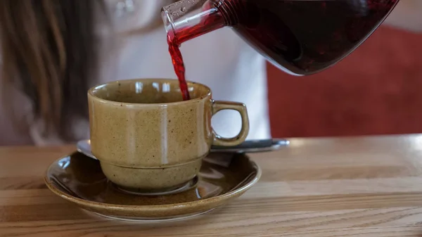 Chica vertiendo té rojo en la taza en la cafetería — Foto de Stock