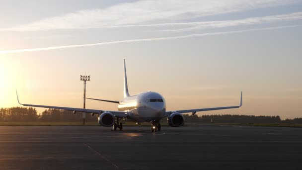 Großes weißes Flugzeug bereitet sich auf seinen Flug vor und setzt sich bei Sonnenuntergang auf der Landebahn in Bewegung. — Stockvideo