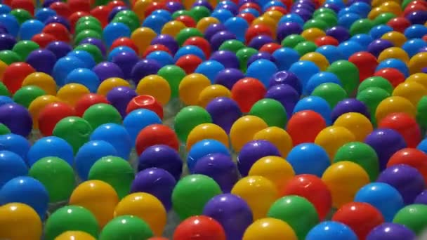Coloridas pequeñas bolas de plástico flotando y moviéndose en el agua, vista de cerca . — Vídeos de Stock