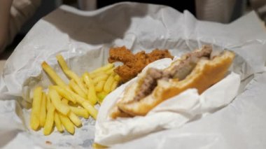 Fast food kafede patates kızartması, tavuk ve hamburger yiyen kadın, yemek yakın çekim.