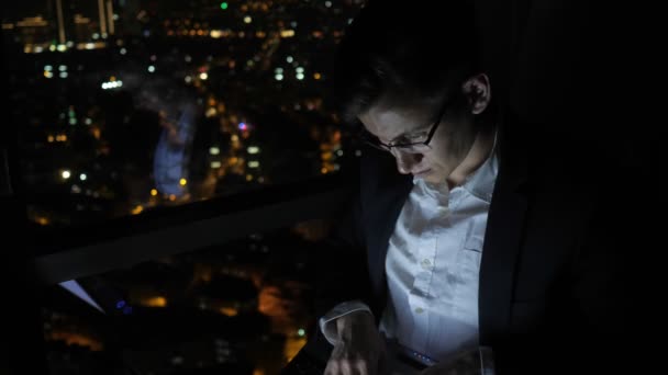 Joven freelancer está trabajando en su ordenador cerca de la ventana en casa por la noche . — Vídeo de stock