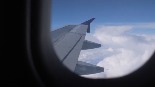 Blick aus dem Flugzeugfenster auf Flügel, Himmel und Wolken. — Stockvideo