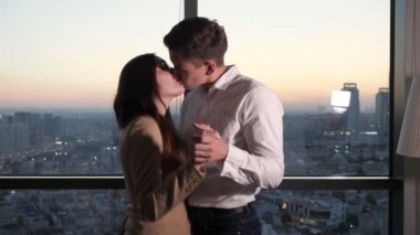 Çift, erkek ve kadın dans ve şehir manzaralı panoramik pencere yakınında öpüşme.