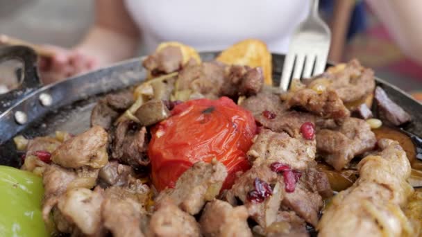 Mujer comiendo carne con verduras servidas en sartén en restaurante, primer plano . — Vídeos de Stock