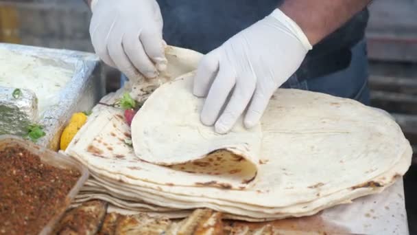 Man is cooking making ekmek with fish at street market, hands in gloves closeup. — Stock Video