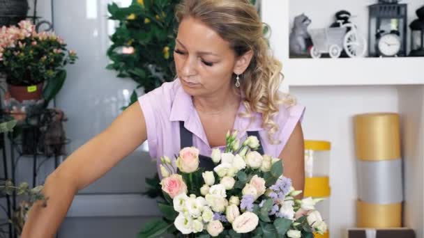 Bloemist vrouw creëert mooie bloem boeket met rozen, bladeren en Gypsophila. — Stockvideo