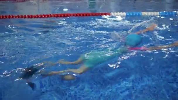 Mädchen mit Brille, Badekappe und Schwimmflossen trainiert Schwimmen im Pool. — Stockvideo