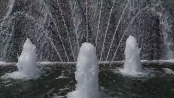 Fontána se zdvihajícími vodními tryskami a stěnou s padající vodou, pohled na sraženku. — Stock video