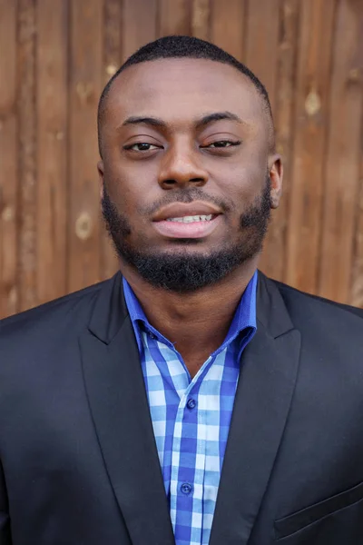 Afro american man in suit smiling and looking at camera on dark wood background. — Stock Photo, Image