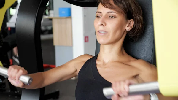 스포티 한 여자는 훈련 기계에 팔 근육에 대한 운동을하고있다. — 스톡 사진