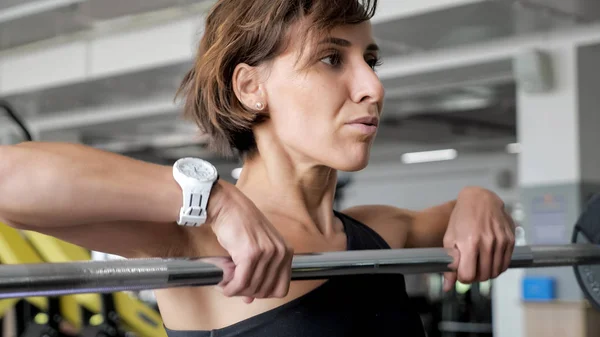 Mulher está levantando barbell fazendo exercícios para ombros . — Fotografia de Stock