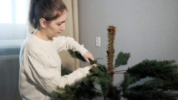 Señora con coleta inserta rama artificial árbol de navidad — Vídeo de stock