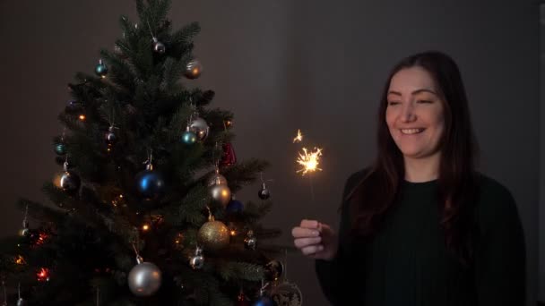 Pretty lady in green sweater holds bright burning sparkler — Stock Video