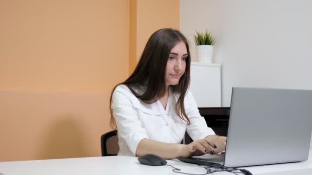 Beauty salon receptionist types on grey modern laptop — Stock Video