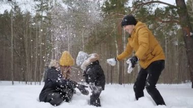 Anne ve baba yavaş çekimde oğulları için kar yağışı yapıyor bir kar atıyorlar.