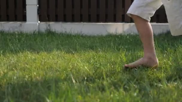 Niño pequeño con los pies desnudos sucios corre rápido sobre hierba verde — Vídeo de stock