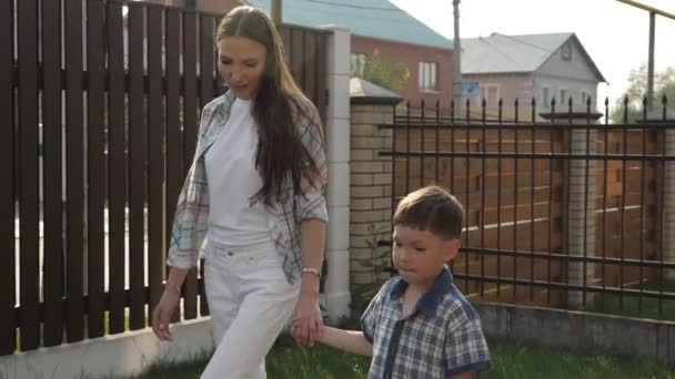 Mamma med löst mörkt hår rymmer bedårande liten pojke hand — Stockvideo