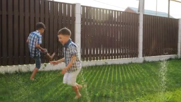 Glimlachend kleine jongens lachen lopen langs groene werf gazon — Stockvideo