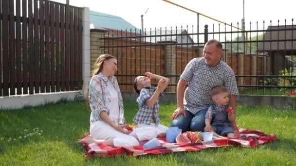 Niños pequeños felices disfrutan de picnic con la madre padre riendo — Vídeos de Stock