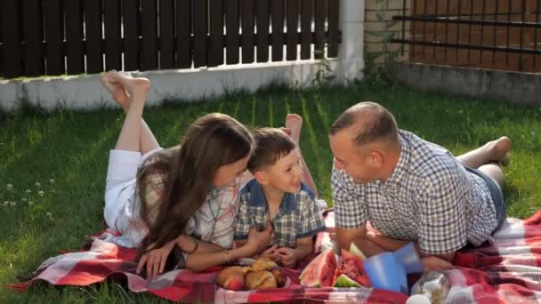 Familia feliz miente habla y se ríe en manta brillante — Vídeos de Stock