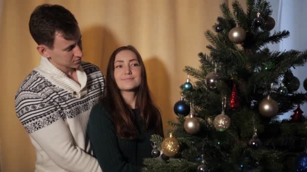 Joven mujer y hombre abrazo y beso cerca de árbol de Navidad — Vídeos de Stock